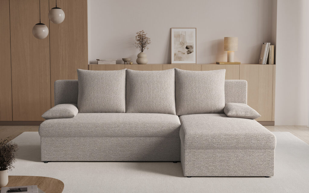 Light grey L-shaped sofa in a minimalist living room with wooden cabinets and neutral decor.
